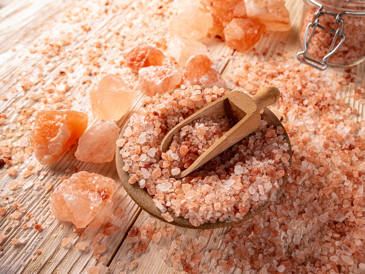 Pink himalayan salt with a wooden scoop on a wooden surface