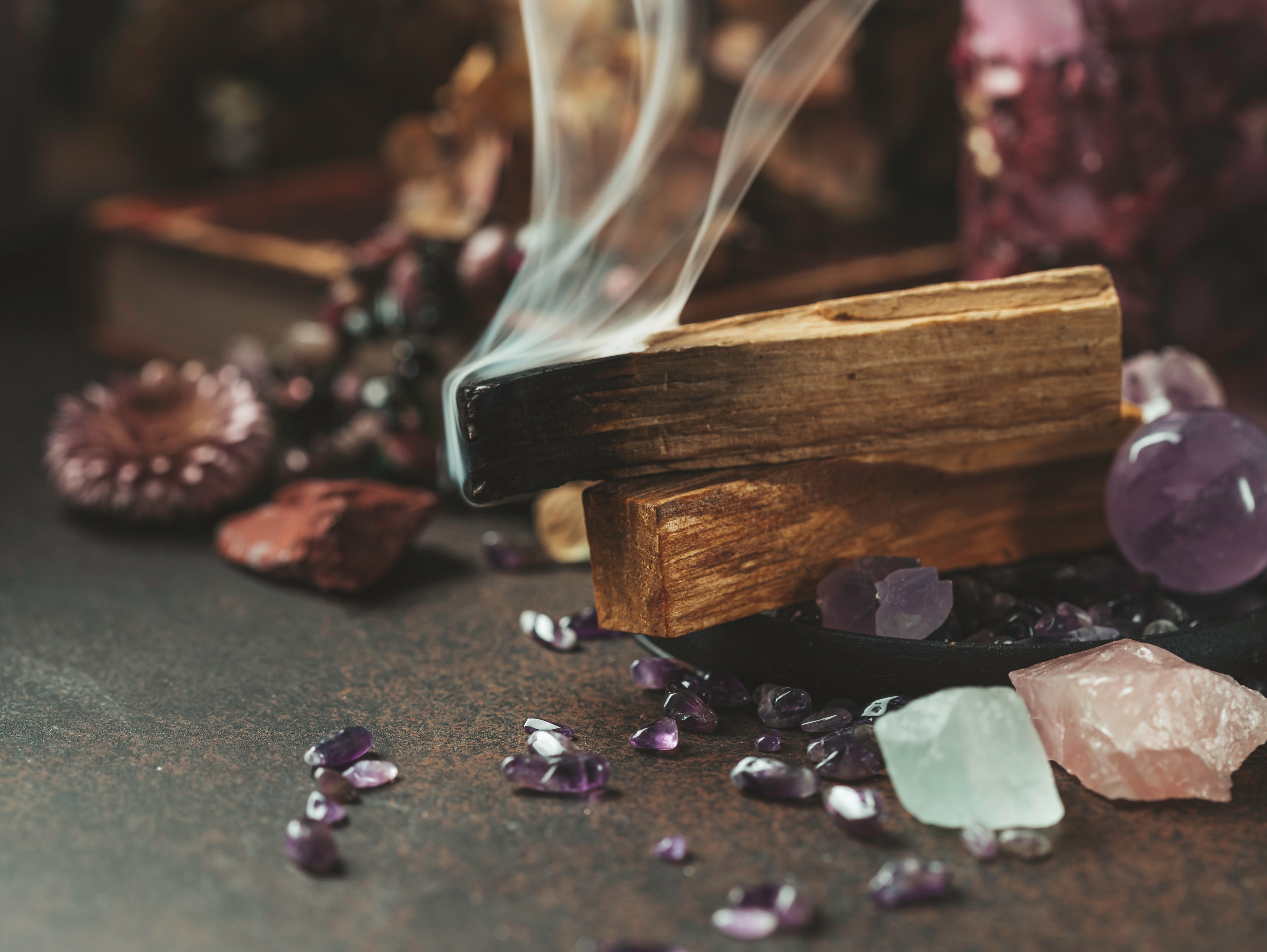 Incense stick burning with crystals and stones on a dark surface