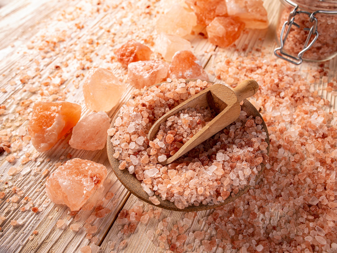 Pink himalayan salt with a wooden scoop on a wooden surface